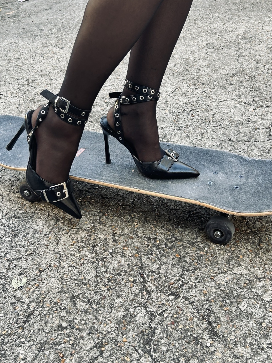 Escarpins noirs et skateboard sur le bitume